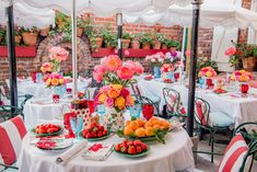 an outdoor dining area with tables covered in flowers and fruit