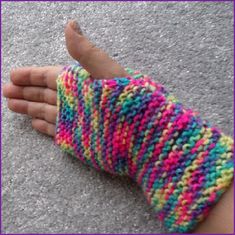 a hand that is wearing a colorful knitted arm warmer