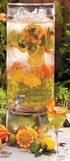 a pitcher filled with water and fruit sitting on top of a table next to wine glasses