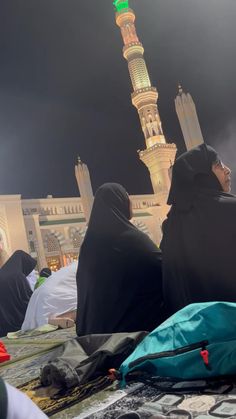 two women sitting on the ground in front of a tall building with a green dome