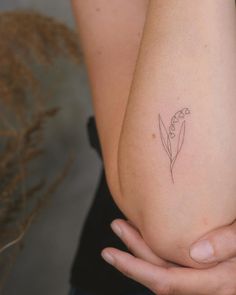 a woman's arm with a small flower tattoo on the left side of her arm