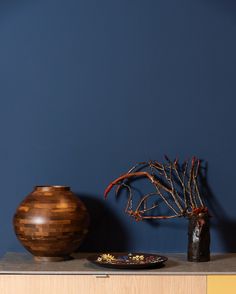 a wooden vase sitting on top of a table next to a plate and planter