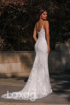 a woman in a white wedding dress standing on the street with her back to the camera