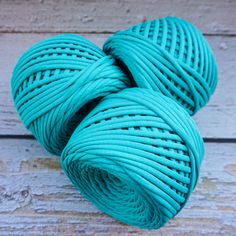 two skeins of yarn are sitting on a wooden surface, one blue and the other green