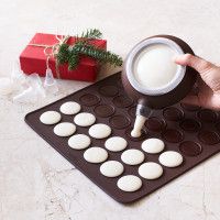 a person pours milk into a cup in front of a chocolate muffin tray