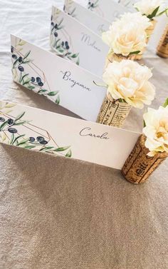 place cards are placed in corks with flowers on the table top for guests to sign