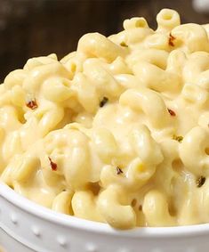 a white bowl filled with macaroni and cheese on top of a wooden table