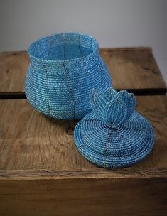 a blue basket sitting on top of a wooden table next to a vase with a flower in it