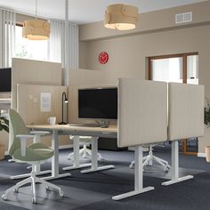 an office cubicle with two computer screens and chairs