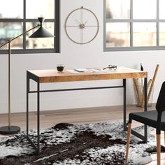 a desk with a chair, lamp and clock on the wall in an empty room