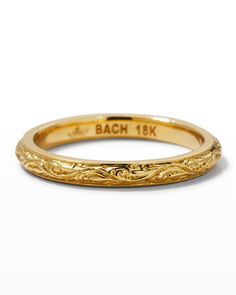 a yellow gold wedding band with an intricate design on the side and engraving in the middle