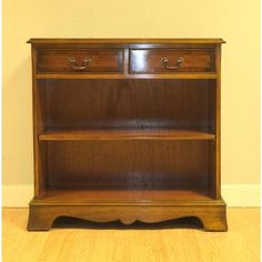 a wooden bookcase with two drawers on the front and one drawer open to show what's inside