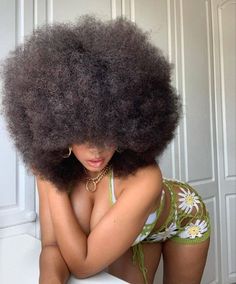 a woman with an afro sitting on top of a white toilet wearing a bathing suit