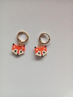 two small orange and white beads are attached to gold hoop earrings