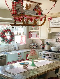 a kitchen decorated for christmas with red and white decorations hanging from the ceiling over the stove