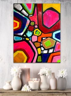 an abstract painting on the wall next to vases with flowers and candles in them