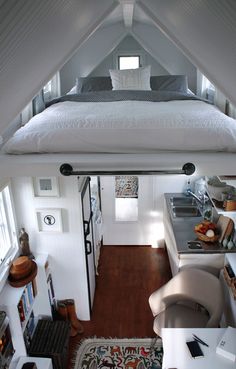 an overhead view of a bedroom with a bed, desk and kitchen in the background
