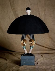 a mannequin dressed in black and green striped tights, holding an umbrella