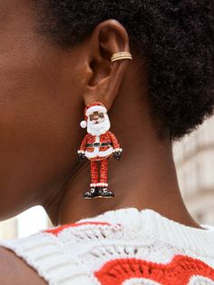 a woman wearing red and white earrings with a santa clause design on the back of her ear