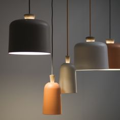 an assortment of different colored lights hanging from the ceiling in front of a gray wall