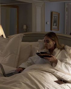 a woman laying in bed with a plate of food