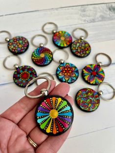 a hand holding a keychain with many different designs on it