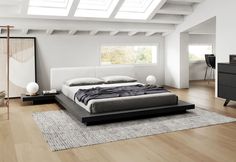 a modern bedroom with white walls and wood flooring, along with a large bed