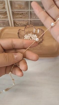 a person holding a spool of thread next to a bowl with pearls on it