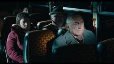 an older man sitting in the middle of a bus with two other people behind him