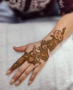 a woman's hand with henna tattoos on her left arm and the top half of