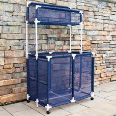 three blue plastic storage bins sitting next to a brick wall