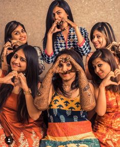 four women are posing for the camera with their hands on their faces and fingers in front of them