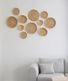 a living room with white walls and wicker plates on the wall above a couch