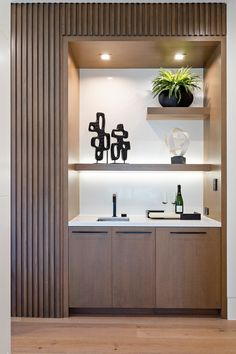 a modern kitchen with wooden cabinets and white counter tops is pictured in this image, there are two vases on the shelves above the sink