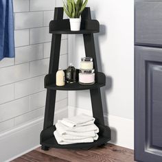 a corner shelf in the bathroom with towels and soaps on it next to a towel rack