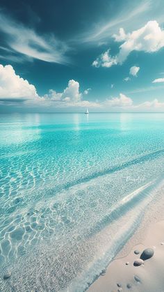 the water is crystal blue and clear with footprints in the sand on the shore line