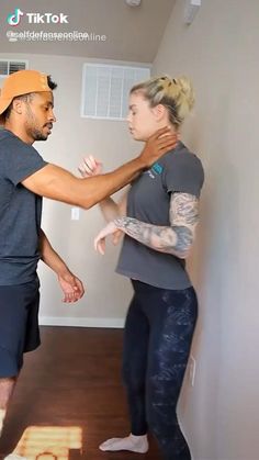 a man and woman standing next to each other in a room with wood flooring