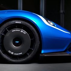 a blue sports car is parked in a dark room with its hood up and wheels down