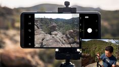 a man is taking pictures with his cell phone while standing on top of a mountain