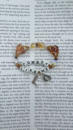 a bracelet with the words cowboy like me on it and charms hanging from it's side