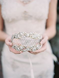 a close up of a person wearing a wedding dress holding something in their hands with pearls on it
