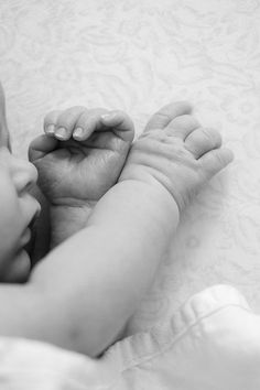 a black and white photo of a baby's hand on top of his head