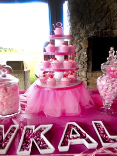 there is a pink cake table with cupcakes on it