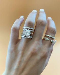 a woman's hand with three different rings on her fingers and one ring in the middle