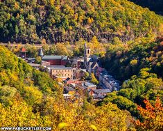 an old town nestled in the mountains surrounded by trees with fall foliage on it's sides