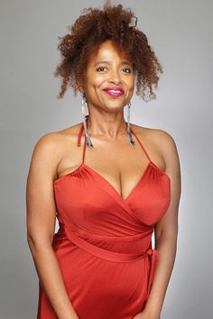 a woman in a red dress posing for the camera with her hands on her hips