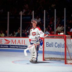 a hockey goalie standing in front of the net with his hands on his hips