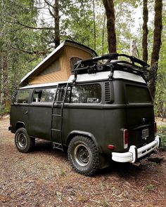 an old van parked in the woods with a tent on top