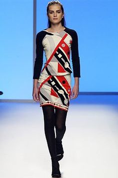 a woman is walking down the runway wearing a dress with an abstract design on it