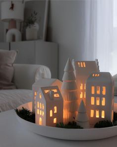 a white plate topped with lit up houses on top of a table next to a window